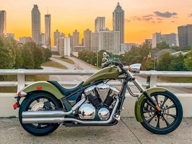 Green American cruiser motorcycle on a bridge at sunset
